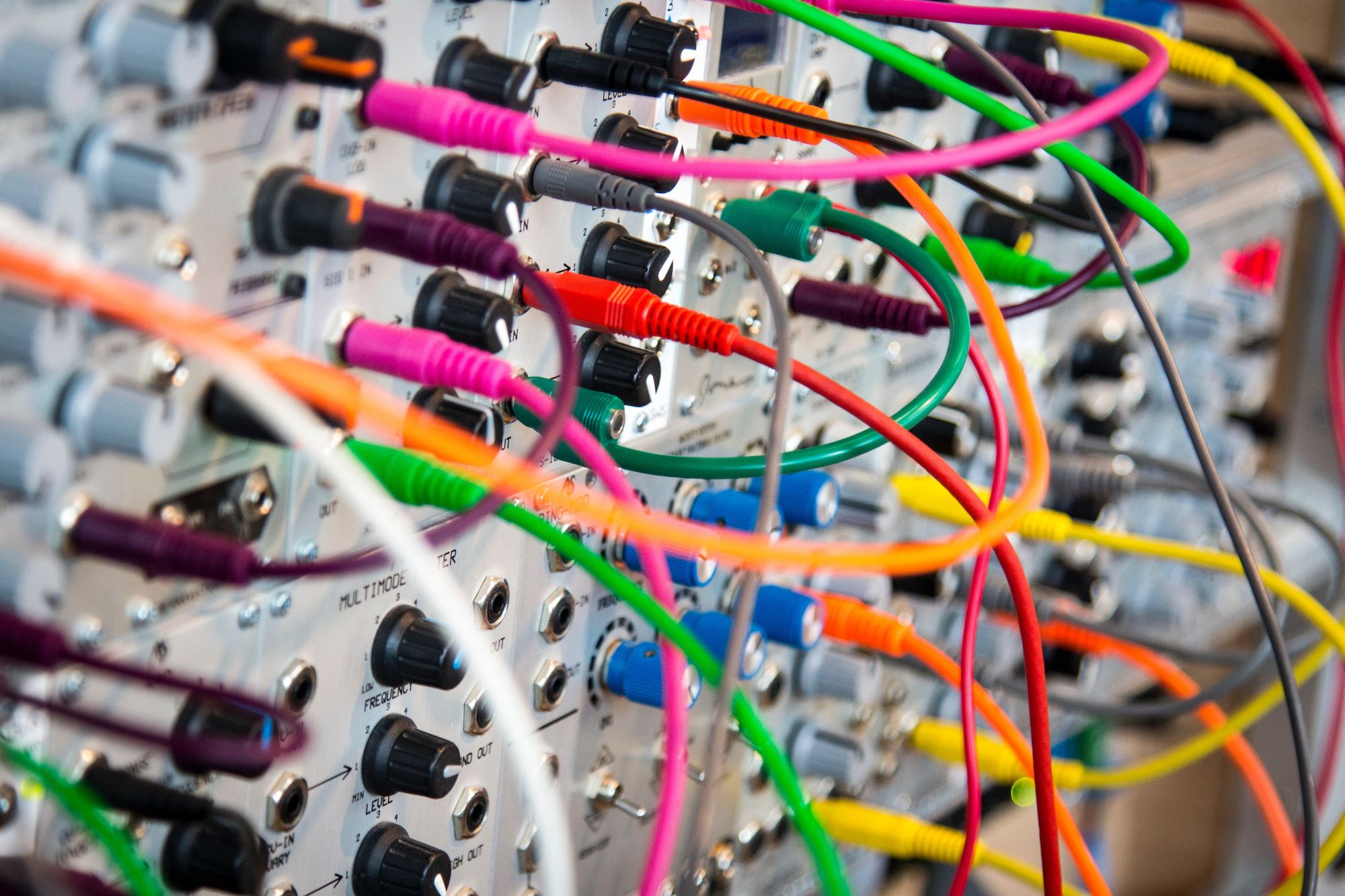 Multiple coloured wires connected to a silver panel with knobs and switches on it